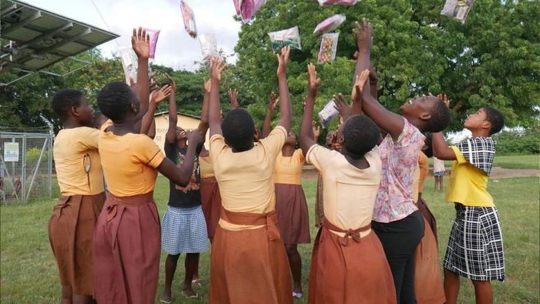 Students in Ghana throw period products in 的 air